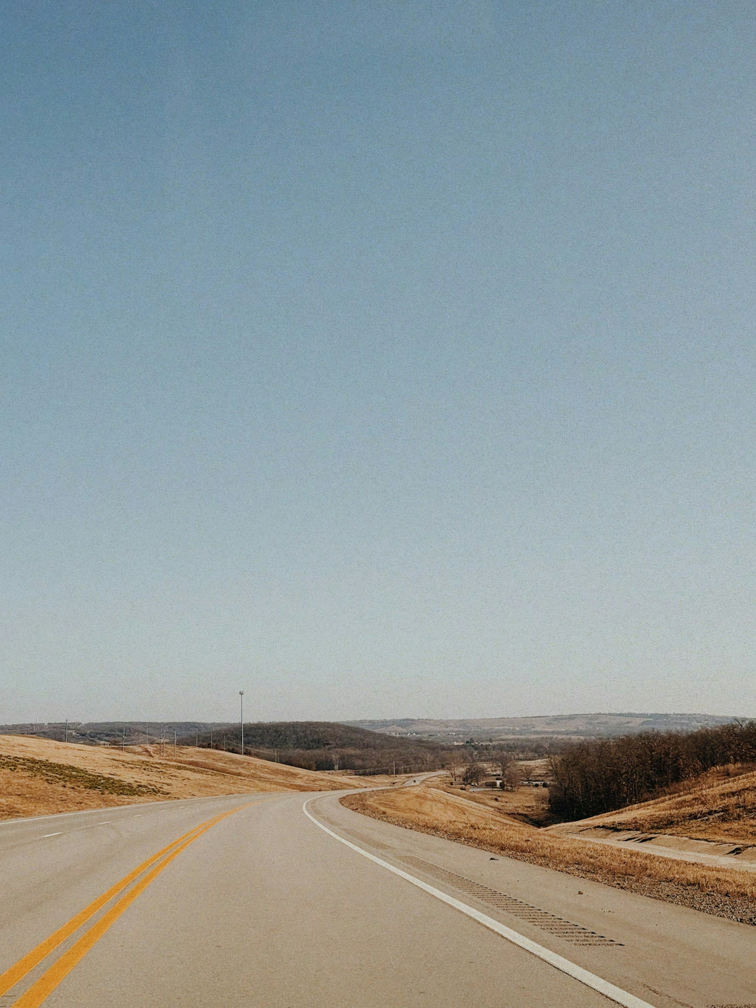 A winding road through rolling hills under a clear sky
